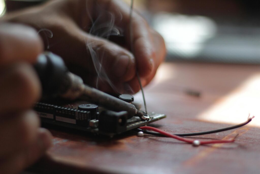 Services Detailed view of soldering process with visible smoke on an electronic circuit board, emphasizing precision.